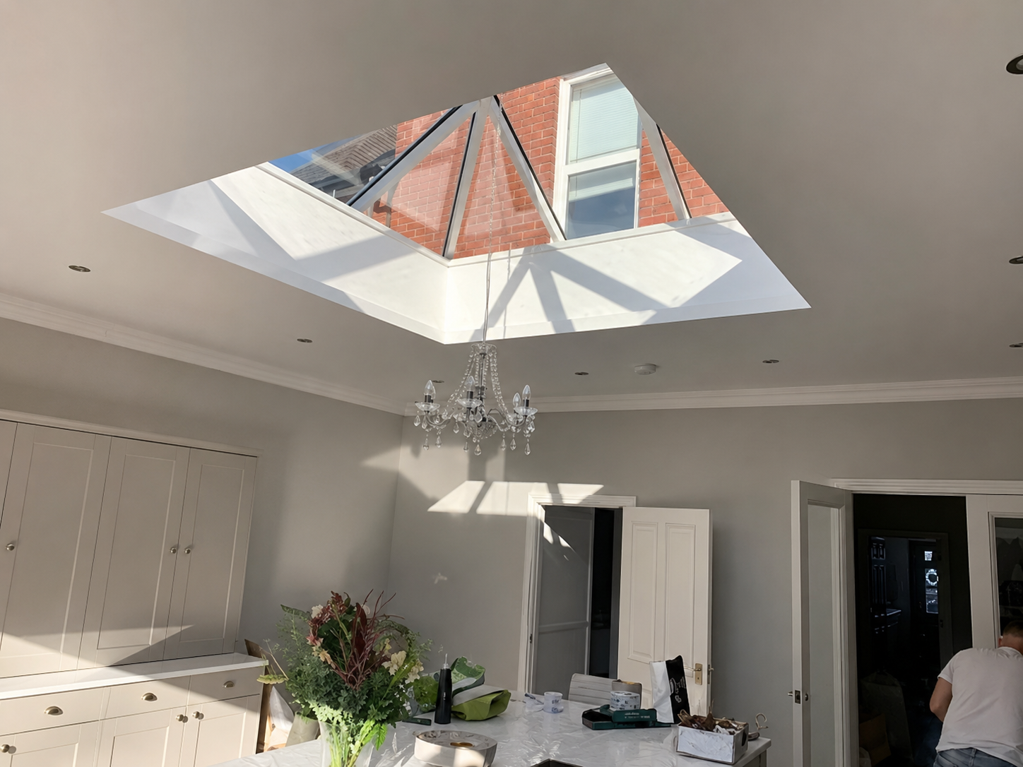 Bright kitchen and dining room with a large roof lantern and chandelier