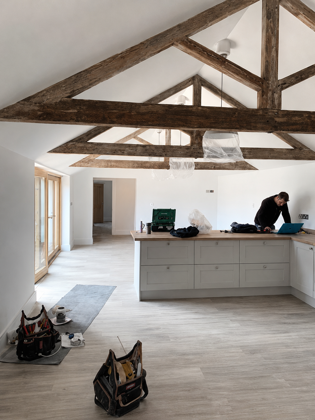 Open-plan kitchen being fitted beneath exposed timber roof beams