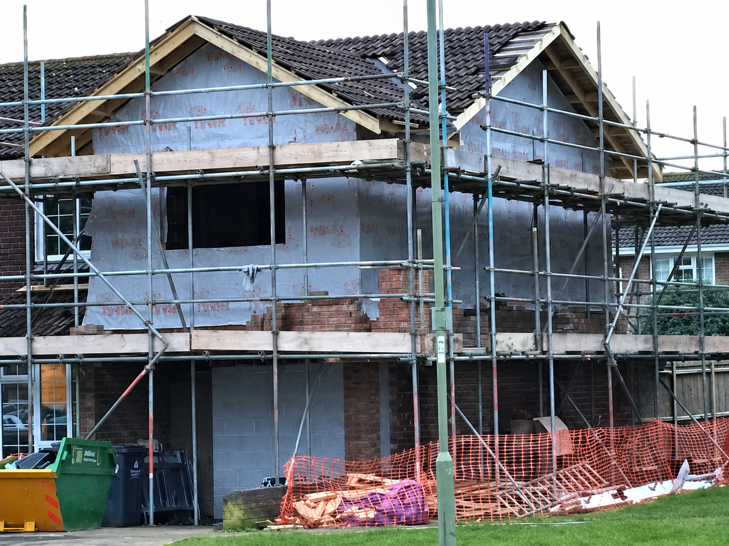 House extension under construction with scaffolding around a timber-framed gable