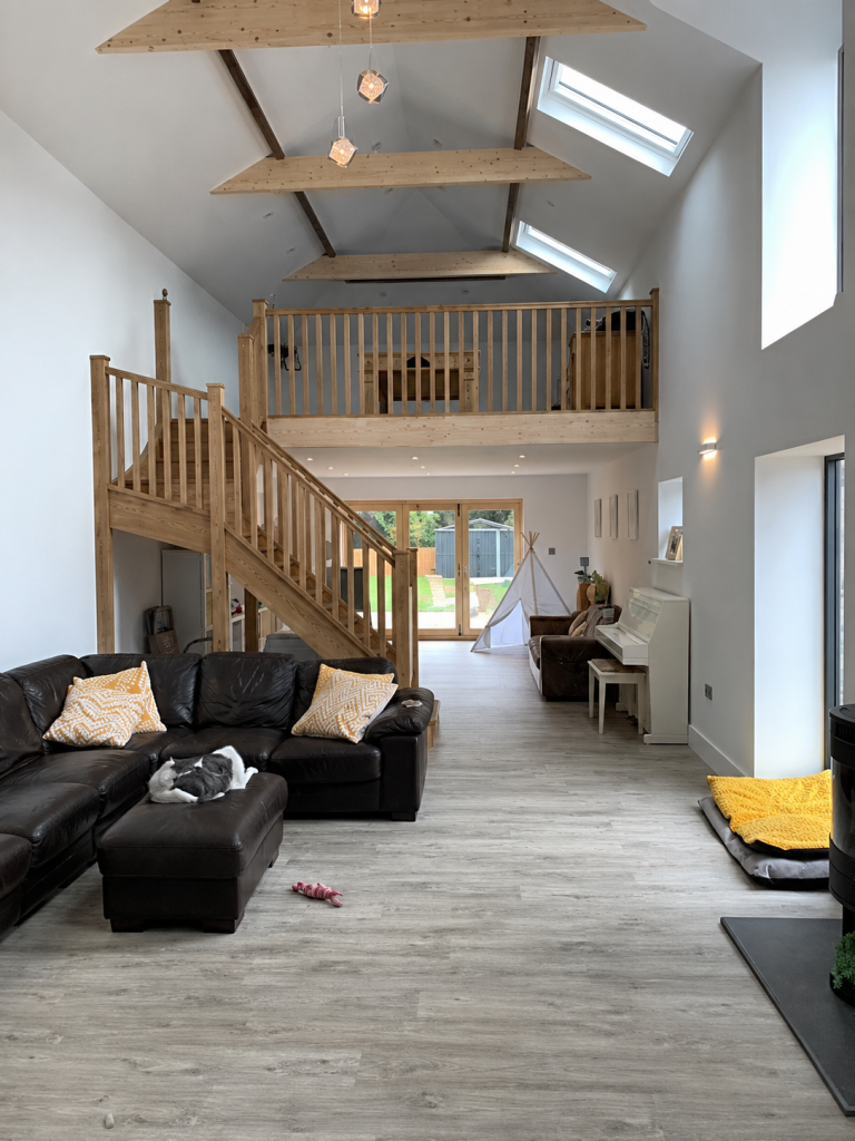 Completed double-height living room with a timber staircase and mezzanine