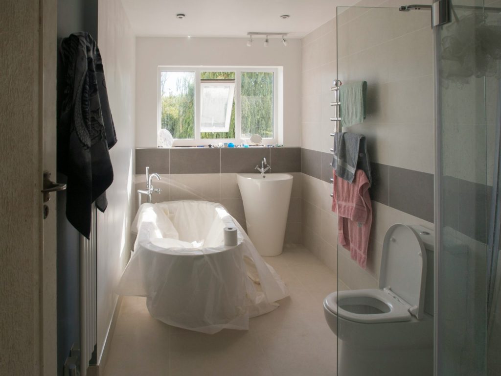 Bathroom refurbishment in progress with a bath, basin, toilet and glass shower screen